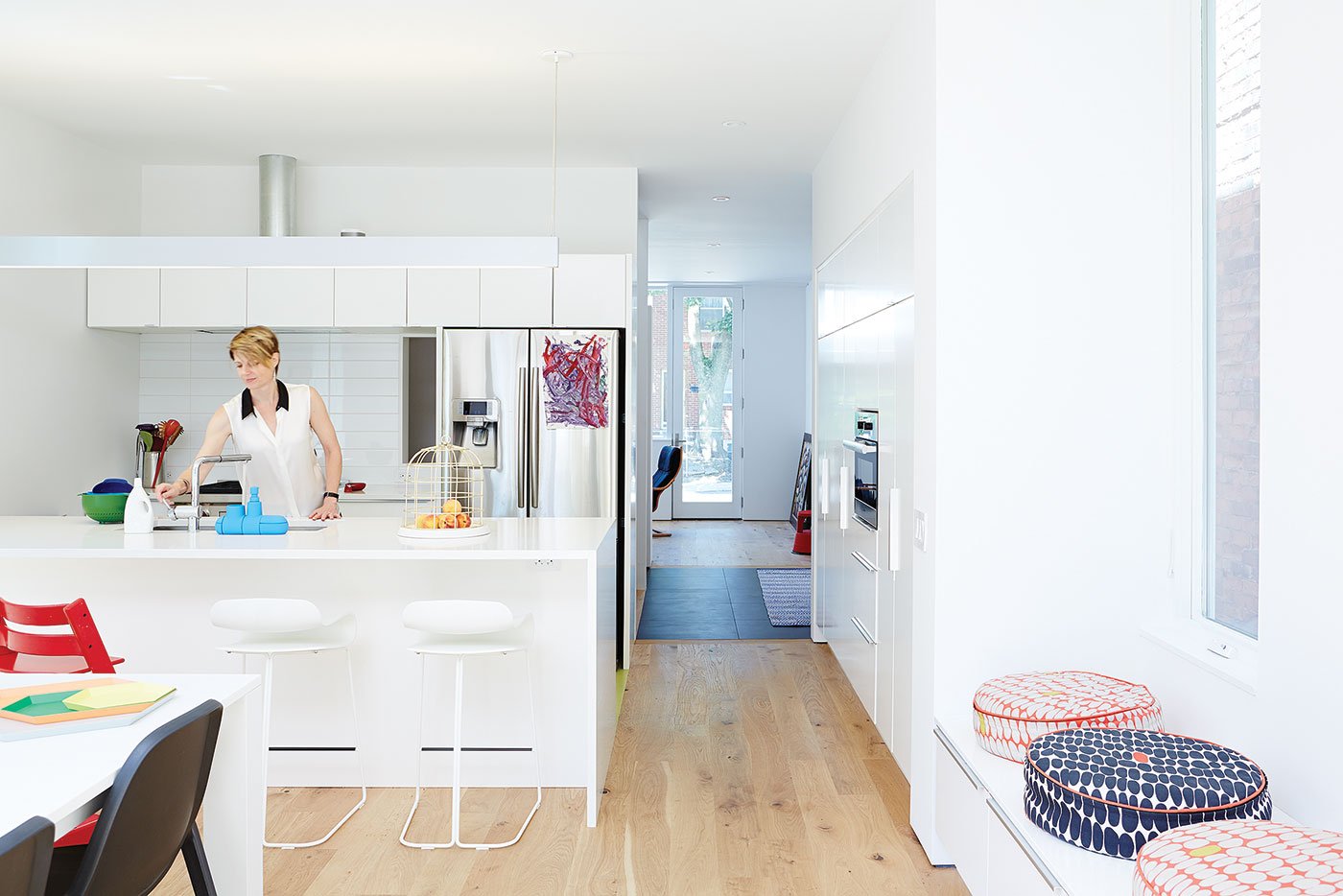 A female person is using the kitchen sink, the cabinetry is white and colourful object are visible | white kitchen Design Ideas