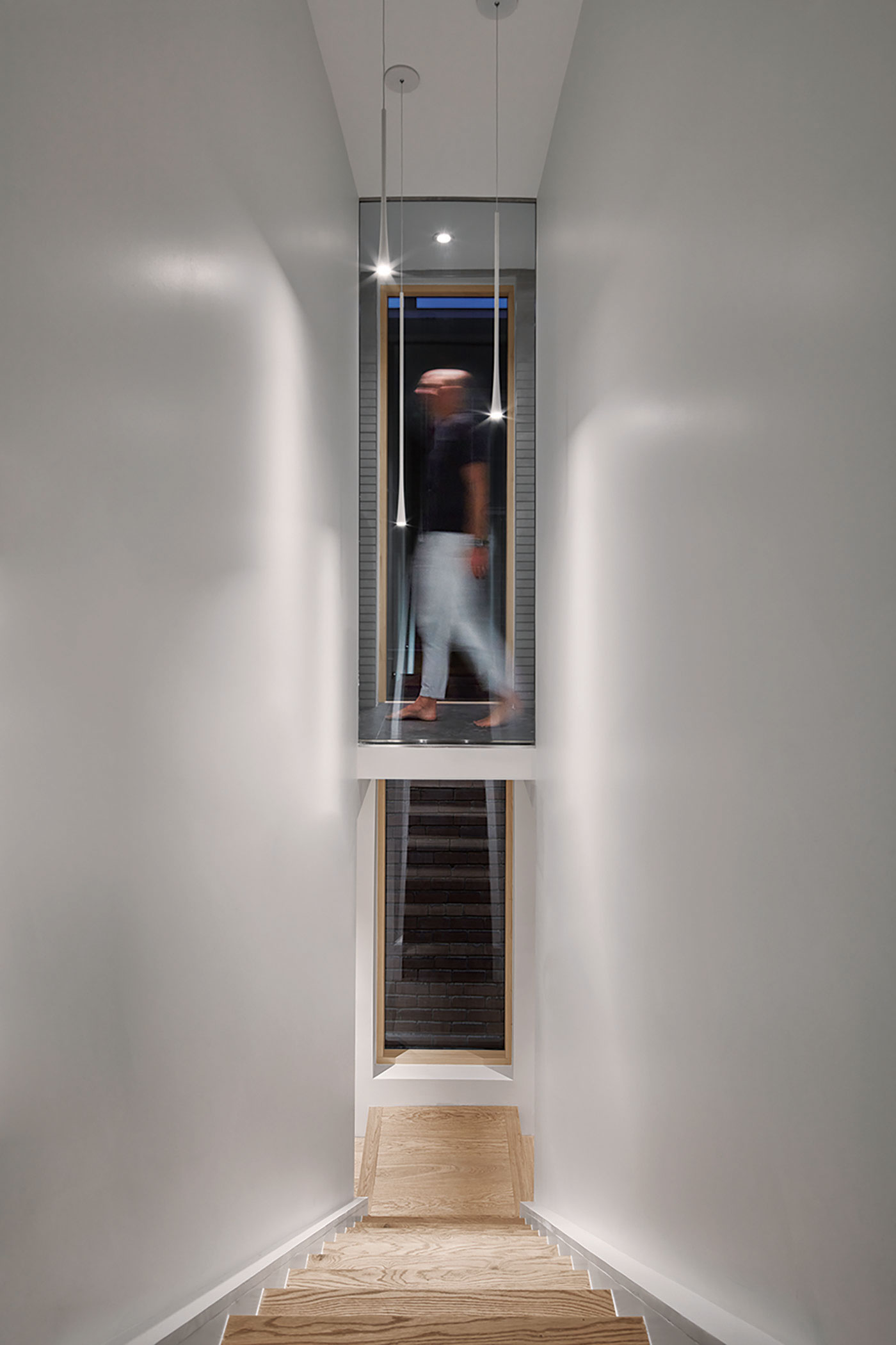 A glass-encased bridge links the principal bedroom with the bathroom while preserving the stairway’s view to the back of the house - Reflect Architecture | Wychwood House