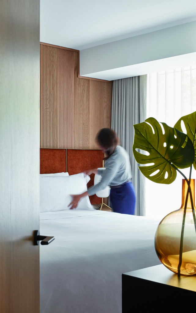 A custom headboard made of mohair fabric panels on a brass plated frame anchors the space at Manulife Centre designed by Alison McNeil